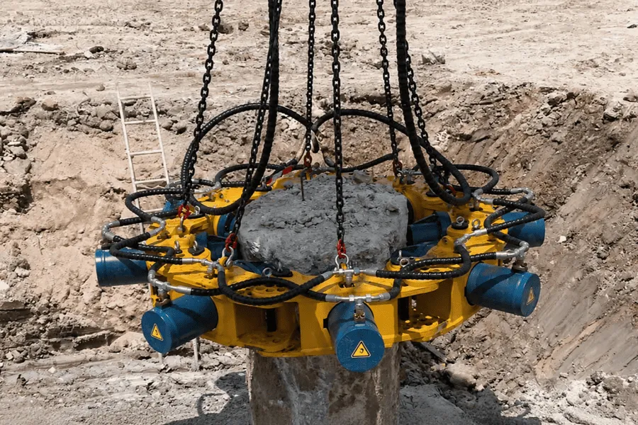 Hydraulic pile breaker installed on a concrete pile during foundation construction